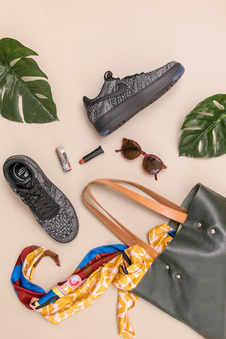 Stylish fashion essentials laid out on a beige surface.